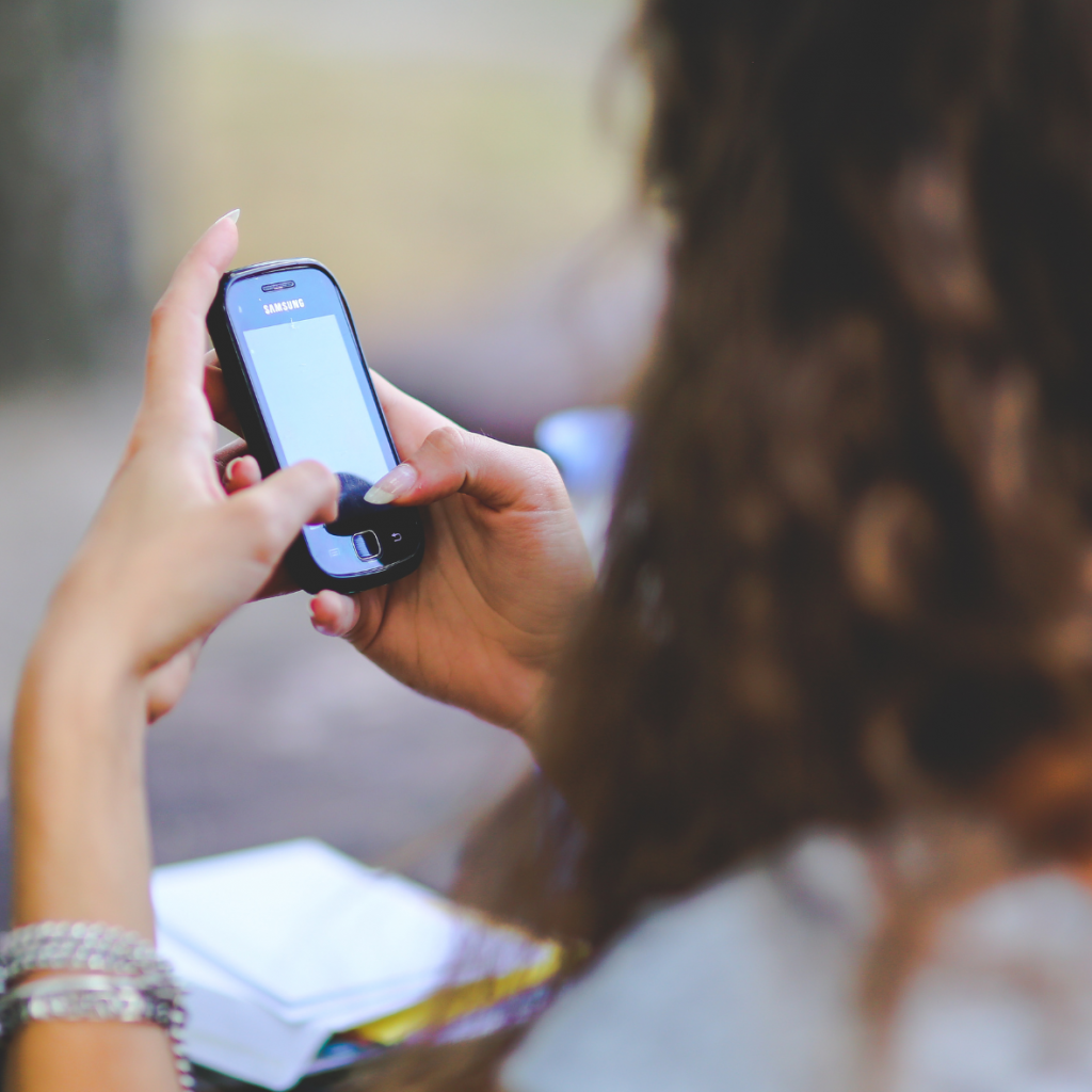 Eine Frau schaut auf Ihr Handy, als w&uuml;rde sie auf eine Nachricht von einem Narzissten warten, der sich getrennt hat und meldet sich nicht mehr